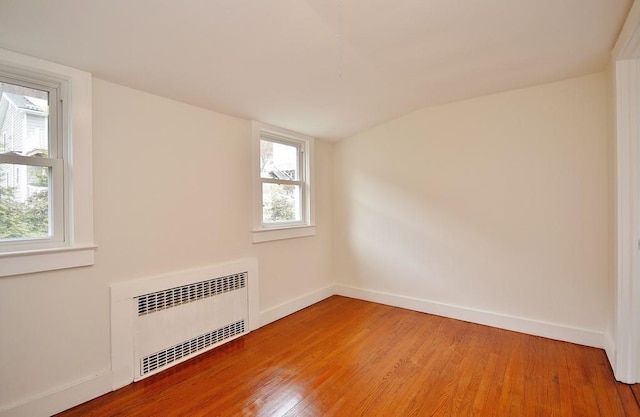 spare room with hardwood / wood-style flooring, lofted ceiling, and radiator heating unit