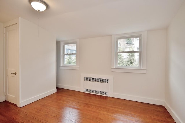 empty room with radiator heating unit and wood-type flooring