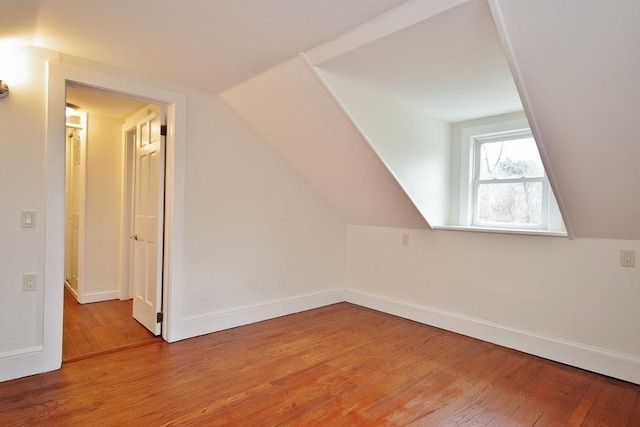 additional living space with wood-type flooring and vaulted ceiling