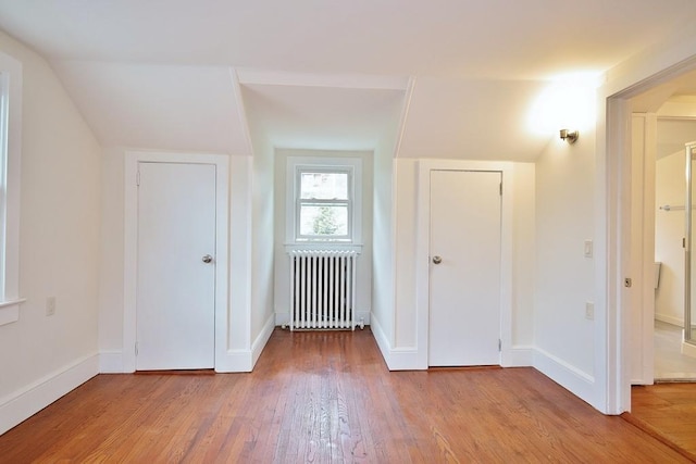 additional living space with radiator and light wood-type flooring