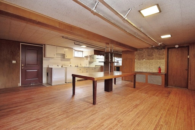 basement featuring washing machine and clothes dryer, light wood-type flooring, and wood walls