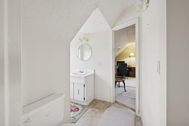 bathroom with vaulted ceiling, toilet, and vanity