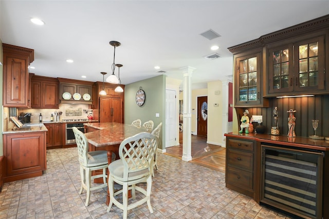 kitchen with stainless steel oven, a center island, pendant lighting, beverage cooler, and light stone countertops