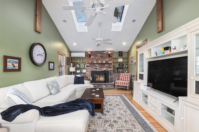 living room featuring an AC wall unit, a skylight, ceiling fan, light hardwood / wood-style floors, and a brick fireplace