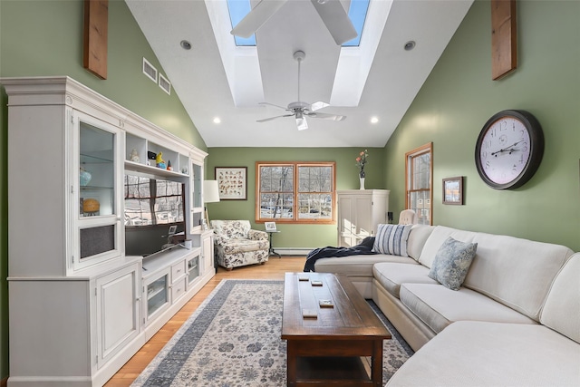 living room featuring ceiling fan, a baseboard radiator, light hardwood / wood-style floors, and vaulted ceiling with skylight