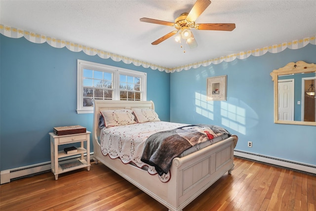 bedroom featuring ceiling fan, wood-type flooring, a textured ceiling, and a baseboard heating unit