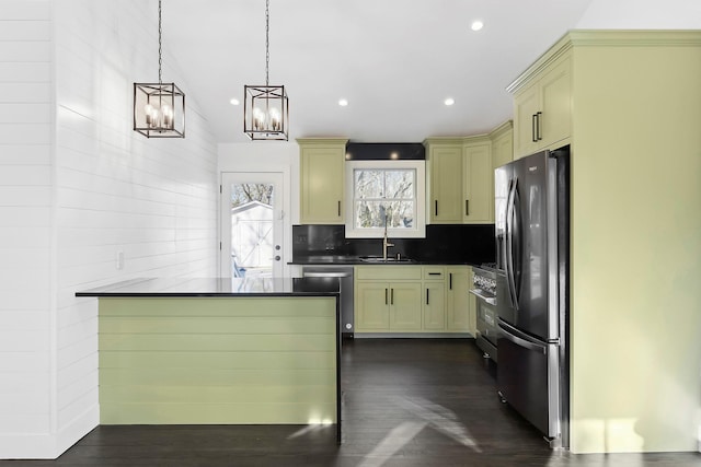 kitchen with sink, dark wood-type flooring, stainless steel appliances, decorative backsplash, and decorative light fixtures