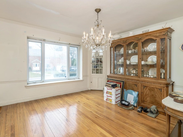 unfurnished dining area featuring crown molding, a chandelier, and light wood-type flooring