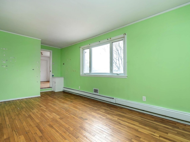 unfurnished room featuring a baseboard heating unit, ornamental molding, and light hardwood / wood-style flooring