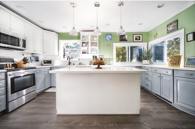 kitchen with decorative light fixtures, gray cabinets, a kitchen island, stainless steel appliances, and white cabinets