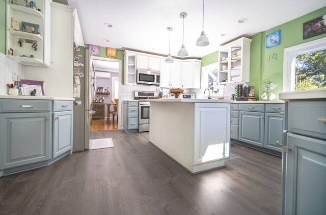 kitchen featuring hanging light fixtures, white cabinets, appliances with stainless steel finishes, and dark wood-type flooring