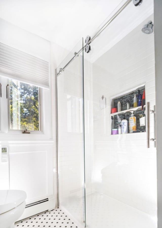 bathroom featuring toilet, baseboard heating, and a shower with door