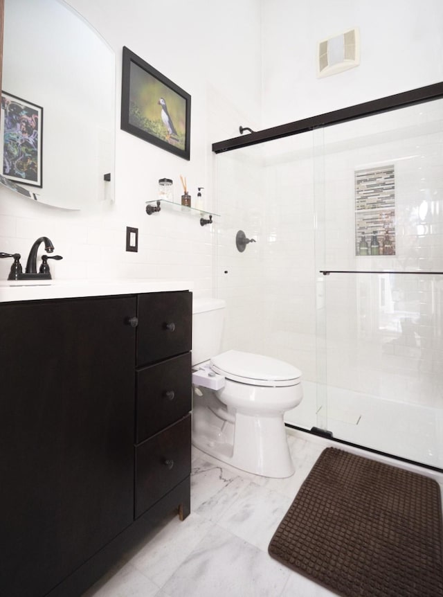 bathroom with toilet, vanity, and a shower with shower door