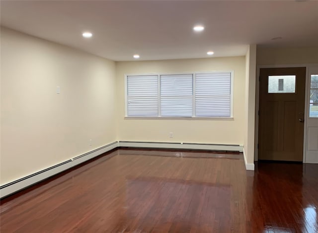 empty room with dark hardwood / wood-style flooring and a baseboard radiator