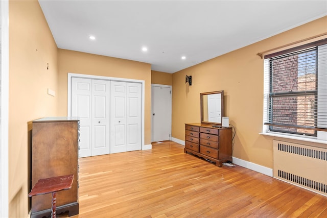 bedroom with radiator heating unit and light hardwood / wood-style flooring