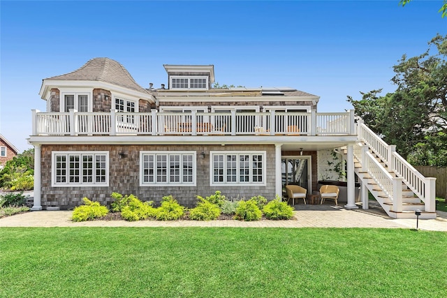 rear view of property featuring a lawn, solar panels, a patio area, and a wooden deck