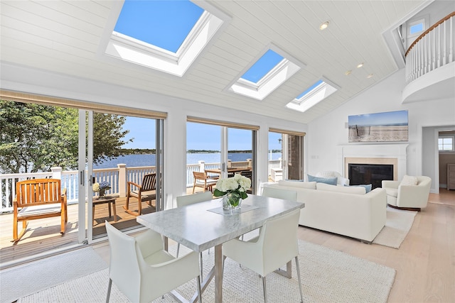 dining space featuring a healthy amount of sunlight, light hardwood / wood-style flooring, high vaulted ceiling, and wood ceiling