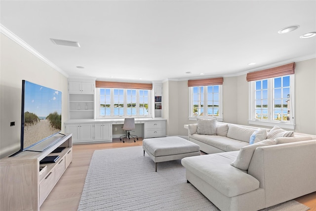 living room featuring built in desk, light hardwood / wood-style floors, and crown molding