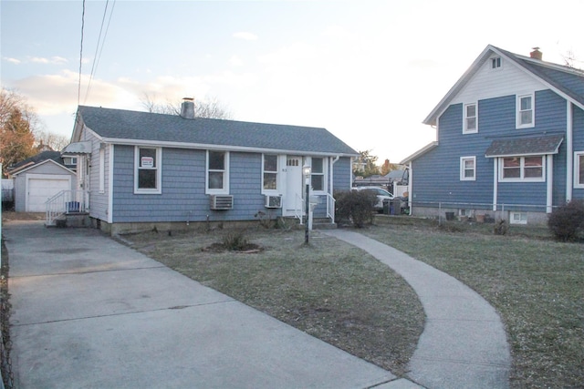 bungalow-style house featuring a garage, cooling unit, a front lawn, and an outbuilding