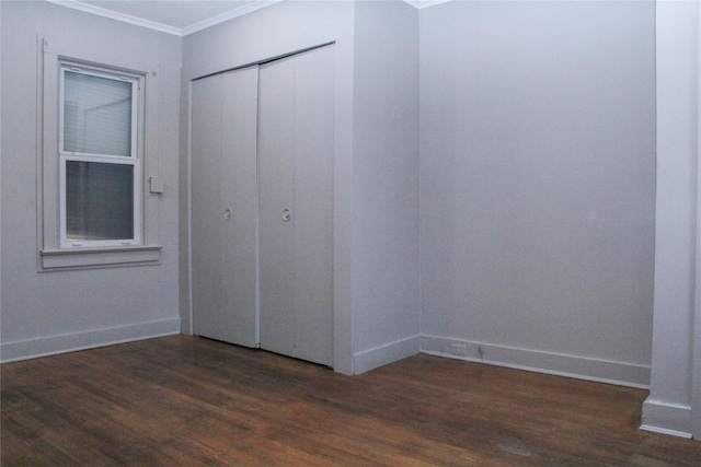 unfurnished bedroom with a closet, dark hardwood / wood-style flooring, and ornamental molding