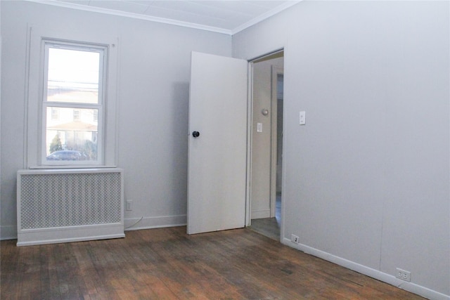 spare room featuring dark wood-type flooring, radiator, and crown molding