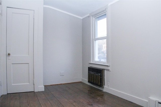 empty room with radiator heating unit, dark hardwood / wood-style flooring, and crown molding