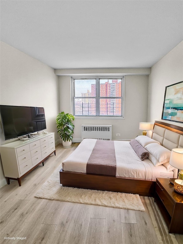 bedroom with radiator heating unit and light hardwood / wood-style floors