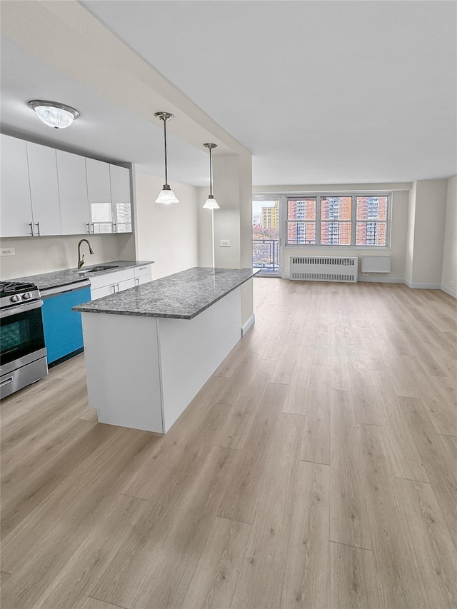 kitchen with stainless steel appliances, decorative light fixtures, white cabinets, radiator heating unit, and a center island