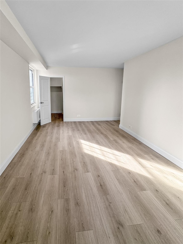 unfurnished bedroom with radiator heating unit and light hardwood / wood-style flooring