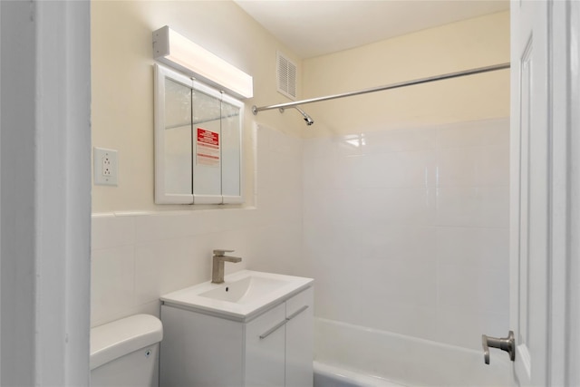 full bathroom with vanity, toilet, tile walls, and tiled shower / bath combo