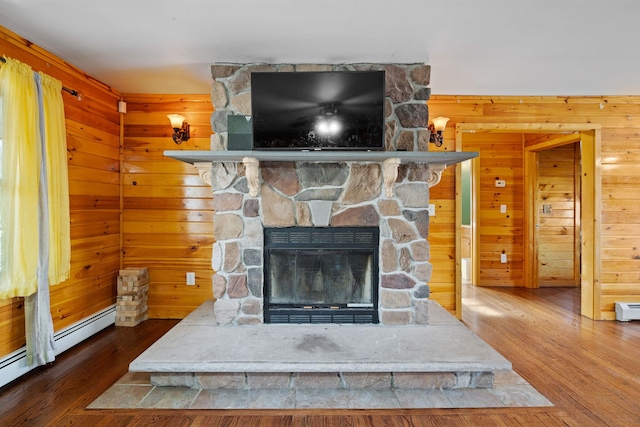 details featuring a baseboard heating unit, wood finished floors, a fireplace, and wood walls