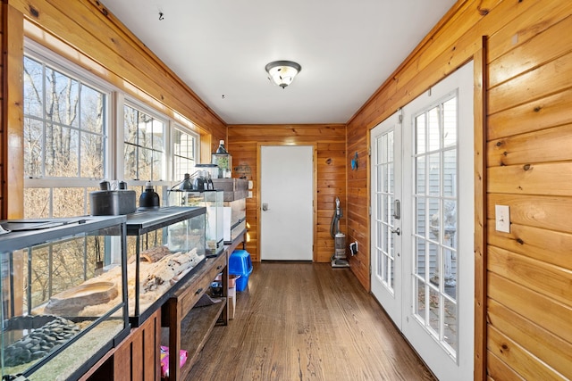 doorway with french doors, wood walls, and dark wood-type flooring