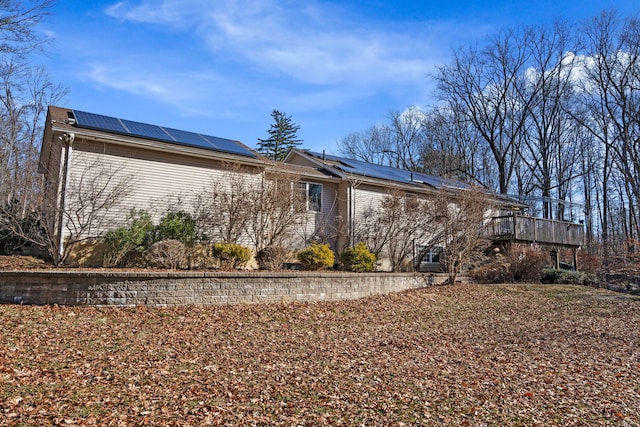 back of house with a deck and roof mounted solar panels