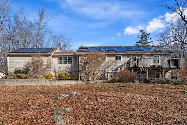 rear view of house with solar panels and a wooden deck