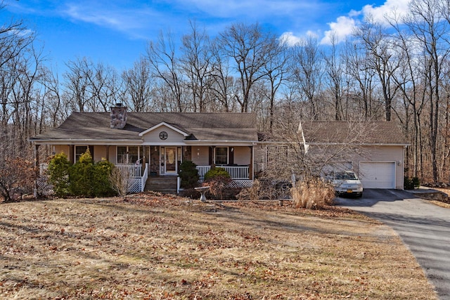 ranch-style home featuring a garage, a chimney, covered porch, and driveway