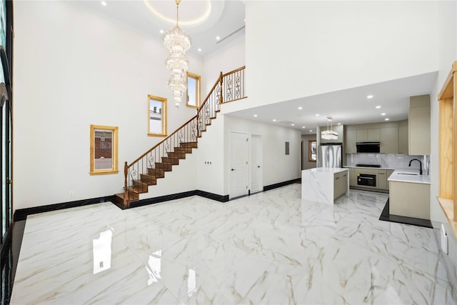 interior space with an inviting chandelier, a towering ceiling, ornamental molding, and sink