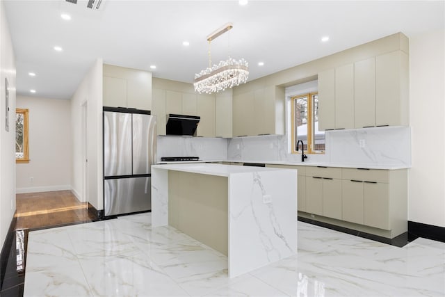 kitchen featuring sink, tasteful backsplash, stainless steel fridge, a kitchen island, and pendant lighting