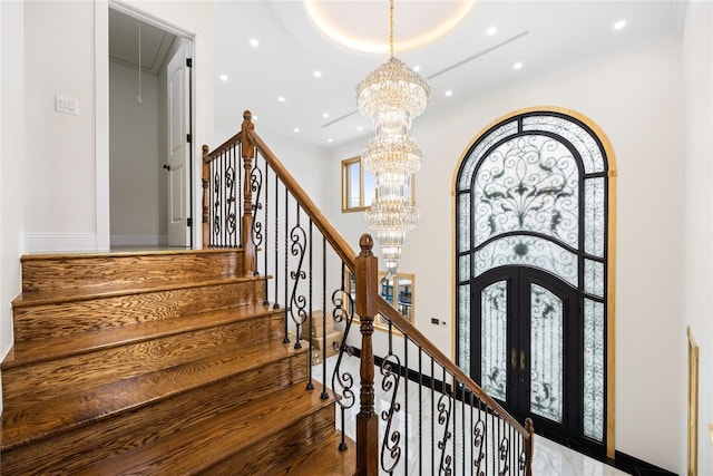 staircase with a high ceiling, crown molding, a chandelier, and french doors