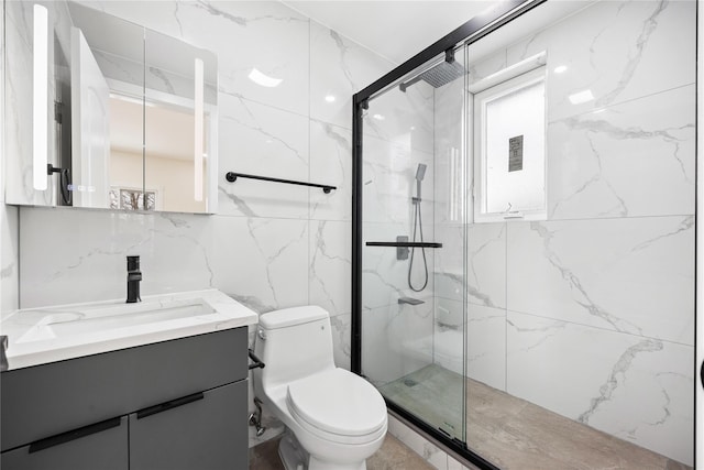 bathroom featuring vanity, toilet, a shower with shower door, and tile walls