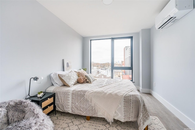 bedroom with a wall mounted air conditioner, light hardwood / wood-style flooring, and vaulted ceiling