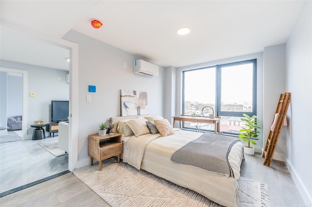 bedroom featuring a wall mounted air conditioner and light hardwood / wood-style floors