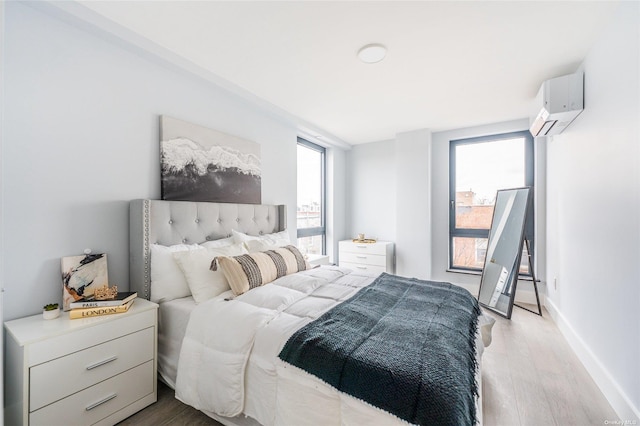 bedroom featuring a wall mounted air conditioner and light hardwood / wood-style floors