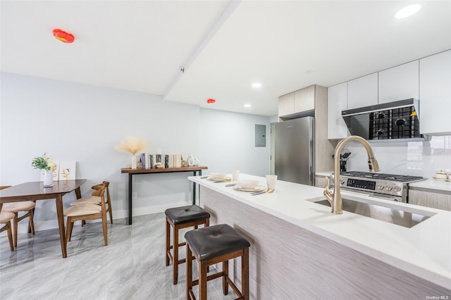 kitchen with stainless steel fridge, backsplash, a breakfast bar area, and sink