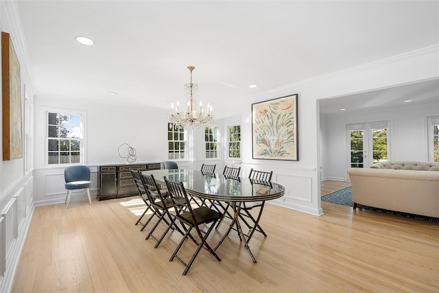 dining room featuring crown molding, light wood-type flooring, a decorative wall, and plenty of natural light