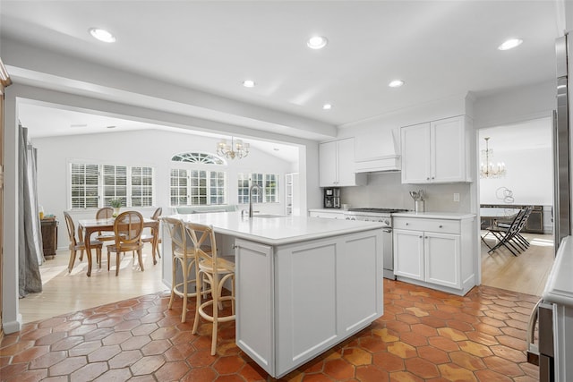 kitchen with lofted ceiling, light countertops, a notable chandelier, and high end stainless steel range