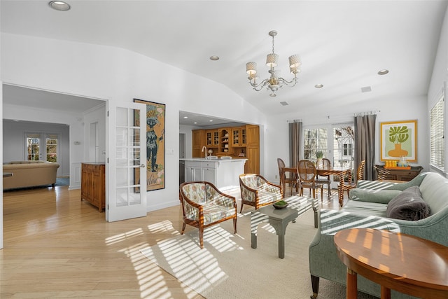 living area featuring recessed lighting, vaulted ceiling, french doors, light wood finished floors, and an inviting chandelier