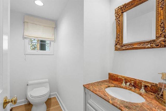 bathroom featuring baseboards, vanity, toilet, and wood finished floors