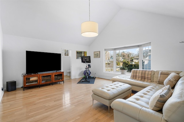 living area with high vaulted ceiling, light wood-type flooring, and baseboards