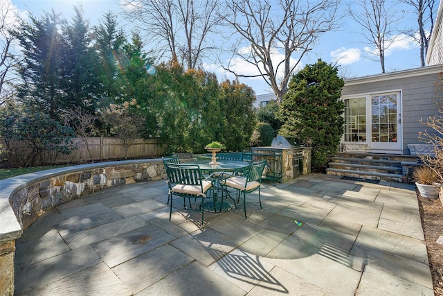 view of patio / terrace featuring grilling area, an outdoor kitchen, entry steps, outdoor dining space, and fence