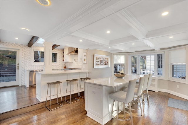 kitchen with a kitchen bar, a spacious island, and wall chimney exhaust hood